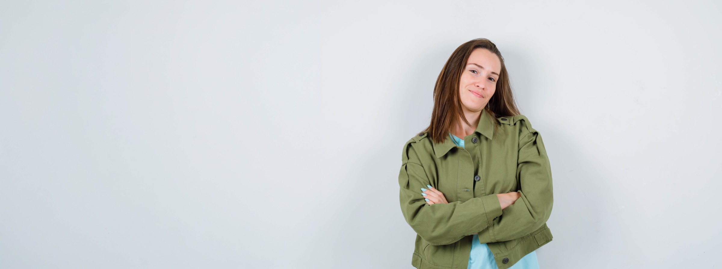 Glimlachende HRM- en recruitmentprofessional met de armen over elkaar, in een groen jack tegen een lichte achtergrond